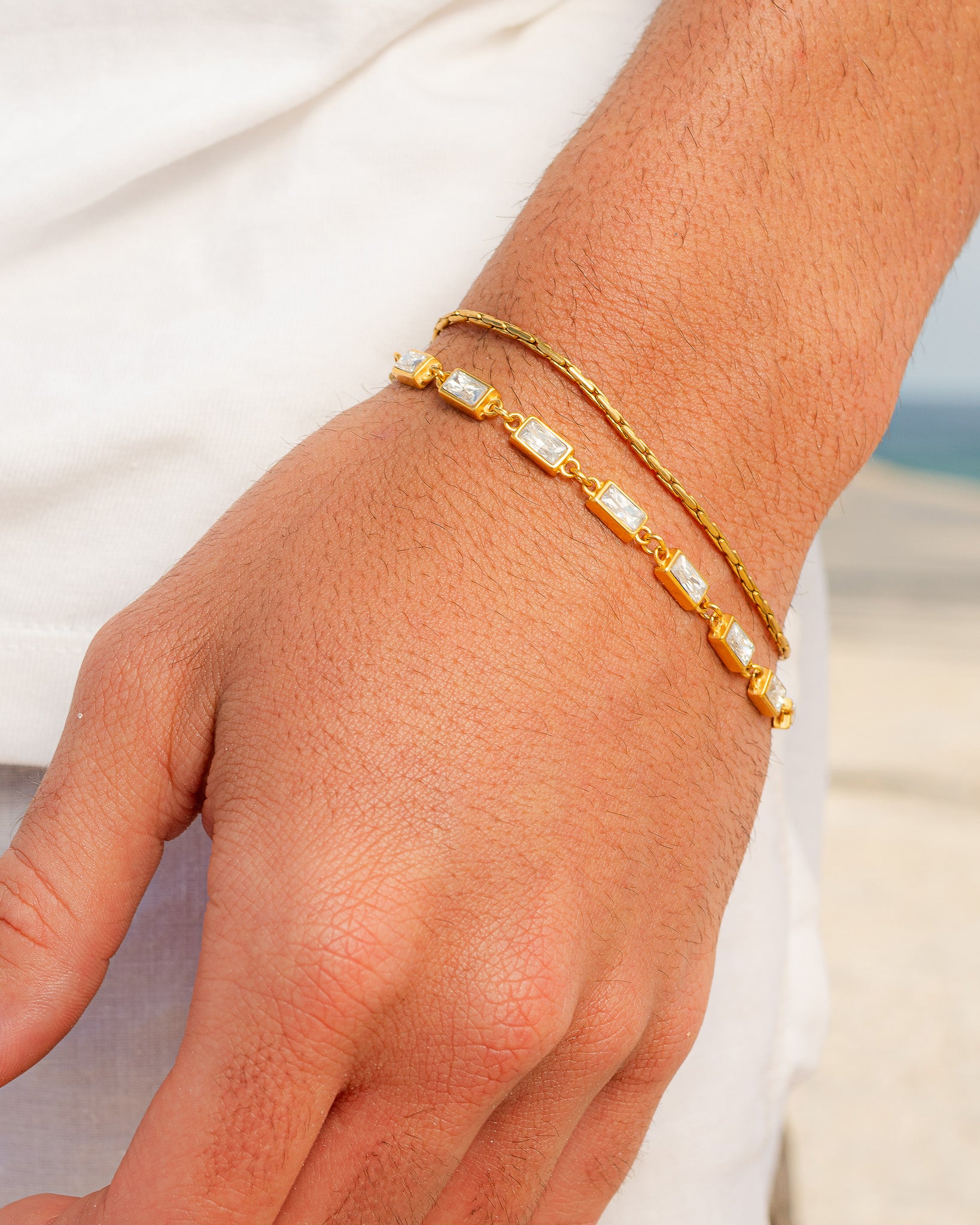 OMEN GOLD BRACELET close up of rectangular clear stones set in gold links on a fine chain