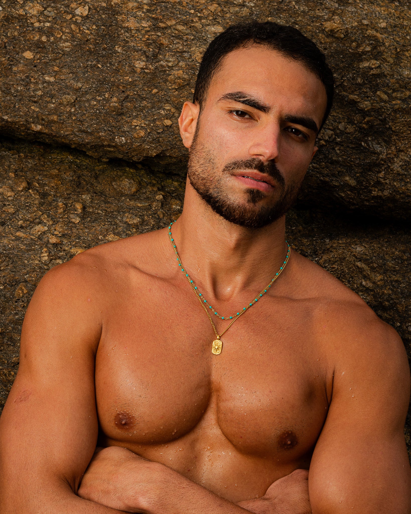 Man on rocky background wearing an IBZ Gold Necklace with turquoise beads and pendant