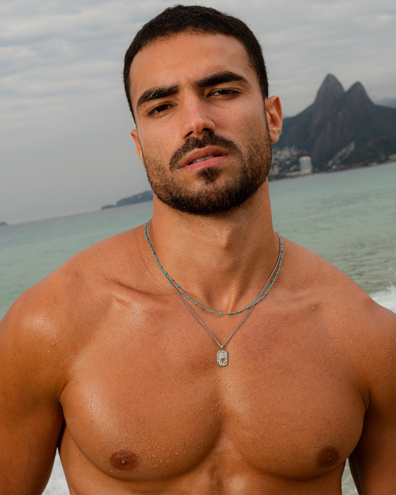 Man wearing a silver necklace with turquoise beads at the beach