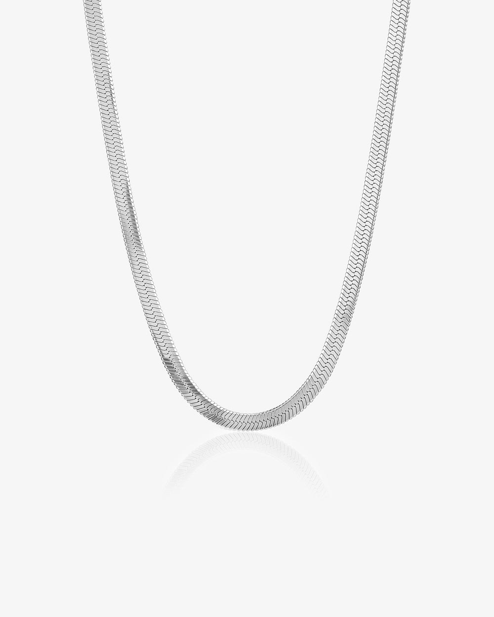Primer plano de un collar de cadena plateada ondulada sobre fondo blanco con reflejo sutil